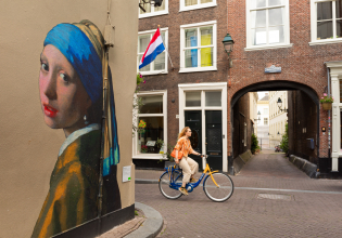 Girl with the pearl mural with person cycling past it